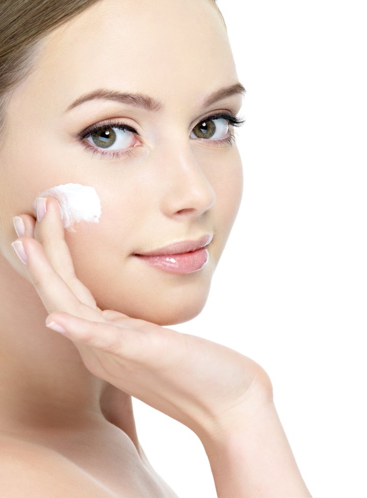 Close-up young beautiful face of girl applying moisturize cream - isolated