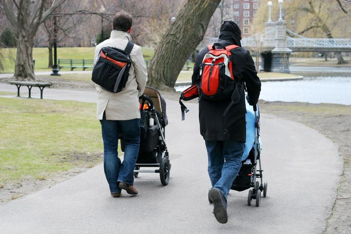 two fathers walking babies in strollers in park