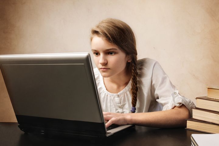 Attentive teenage girl using a laptop