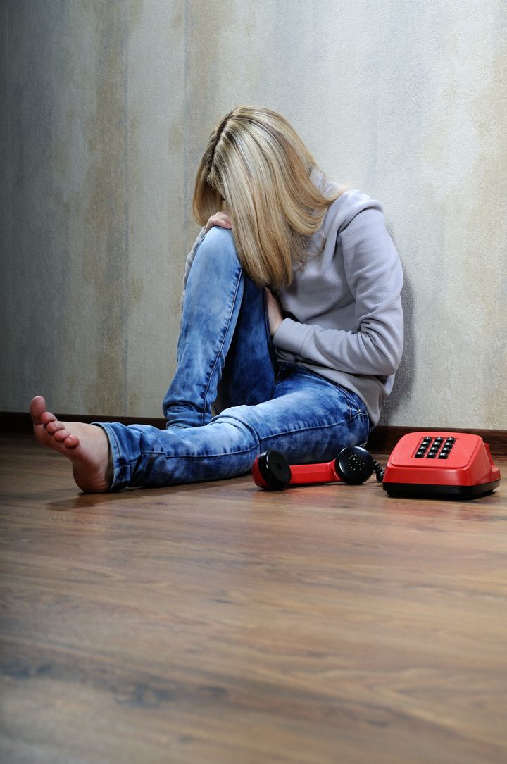 Young woman sitting on a wooden floor with old phone.
