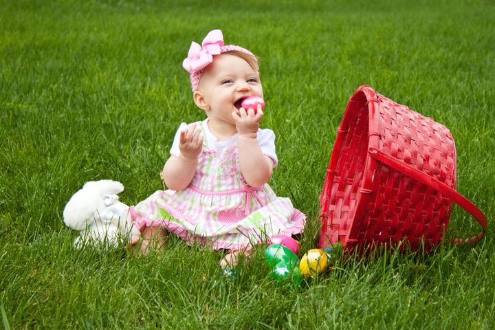 Baby Smiling while holding an Easter egg beside a red basket