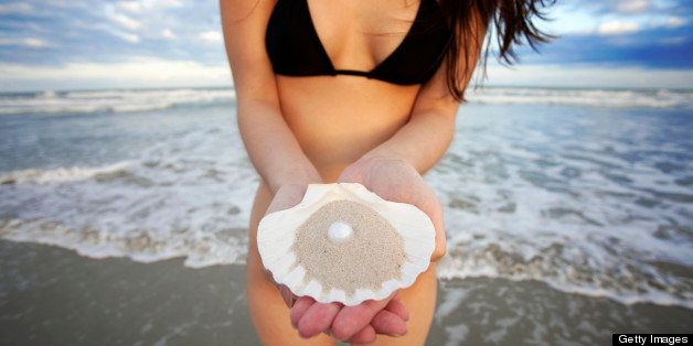 woman in bikini holding shell with pearl at beach