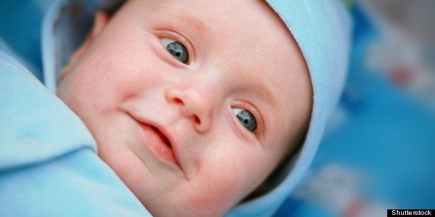 Smiling baby boy with big blue eyes close up