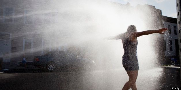 A woman cools off in an open fire hydrant