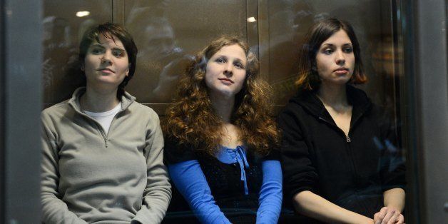 Members of the all-girl punk band 'Pussy Riot' (from L) Maria Alyokhina, Yekaterina Samutsevich and Nadezhda Tolokonnikova sitting in a glass-walled cage in Moscow, on October 10, 2012 . A Moscow court heard today the appeal of feminist punks Pussy Riot against their two-year prison camp sentence, days after President Vladimir Putin appeared to give his blessing to the verdict. AFP PHOTO / NATALIA KOLESNIKOVA (Photo credit should read NATALIA KOLESNIKOVA/AFP/GettyImages)