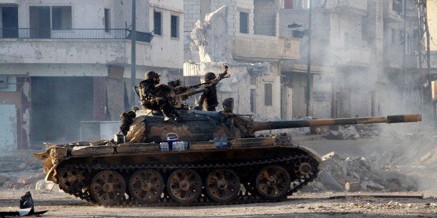 Syrian army troops drive through the ravaged streets of Qusayr in the central Homs province on June 5, 2013, after government forces seized total control of the former rebel-stronghold. The United States condemned the assault by Syrian troops on Qusayr, claiming the regime had had to depend on the Lebanese militant group Hezbollah to win the battle, causing tremendous suffering during a blistering 17-day assault which ended in a major battlefield success for regime forces in a war that has killed at least 94,000 people. AFP PHOTO / STR (Photo credit should read -/AFP/Getty Images)