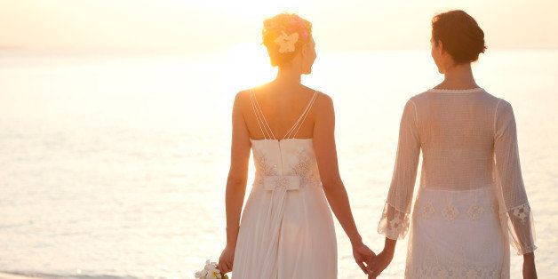 Same sex bridal couple holding hands at sunset