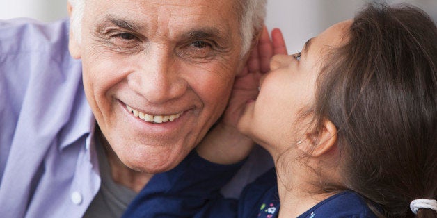 Granddaughter whispering to grandfather