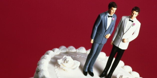 Wedding cake with two groom decorations, pink background