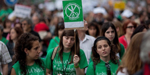 MADRID, SPAIN - MAY 09: A protester (C) holds a placard reading 'Yes to public eductaion, not to cuts' as students and teach