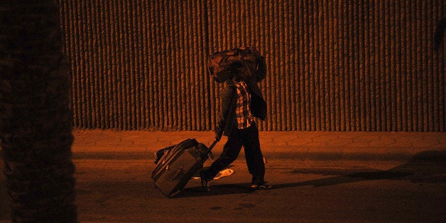 An illegal migrant walsk to a police bus with his belongings on November 13, 2013 before being transferred to a center in the