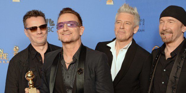 (FROM LEFT): Musicians Larry Mullen Jr., Bono, Adam Clayton and The Edge of U2 pose in the press room after winning the Golden Globe for Best Original Song for 'Ordinary Love' from 'Mandela: Long Walk to Freedom,' in the press room at the 71st annual Golden Globe Awards in Beverly Hills, California, January 12, 2014. AFP PHOTO / ROBYN BECK (Photo credit should read ROBYN BECK/AFP/Getty Images)