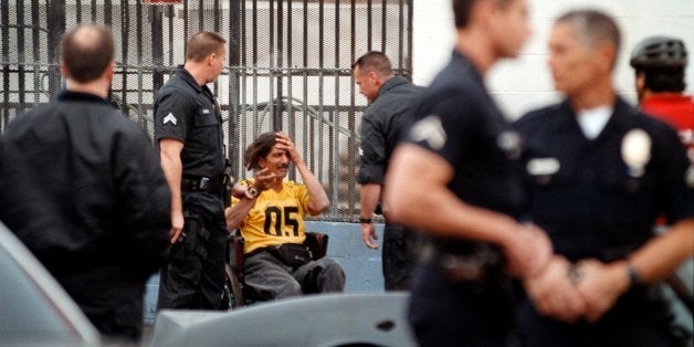 383367 20: Los Angeles Police officers show up in abundance as backup during the arrest of a man in a wheelchair in a very high-crime Skid Row area December 11, 2000 in Los Angeles, CA. The arresting officer holds a gun in his right hand. (Photo by David McNew/Newsmakers)