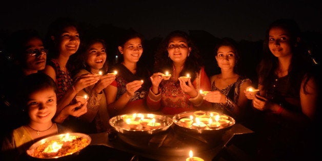 BHOPAL, INDIA - OCTOBER 22: Girls light earthen lamps on the eve of Hindu festival Diwali on October 22, 2014 in Bhopal, India. Prime Minister Narendra Modi has appealed to all Indians that they should buy earthen diyas and lamps from the street sellers instead of imported Chinese lights. Lightning traditional earthen lamps is not only environment friendly but will help in sustaining livelihood of the millions of potters across India who are facing tough time due to increasing use of Fridges and electric lamps. (Photo by Praveen Bajpai/Hindustan Times via Getty Images)