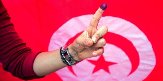 A Tunisian woman shows her ink stained finger after voting at a polling station in Ben Arous,Tunisia, Sunday Oct. 26, 2014. T
