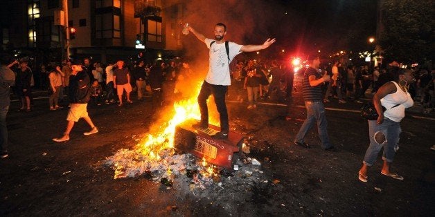 A man stands atop a burning newspaper stand in San Francisco's Mission district in California after the San Francisco Giants beat the Kansas City Royals in the World Series on October 29, 2014. A celebratory mood set the stage for what eventually became a scene of bottle throwing, vandalism, and bonfires throughout the area. AFP PHOTO/JOSH EDELSON (Photo credit should read Josh Edelson/AFP/Getty Images)