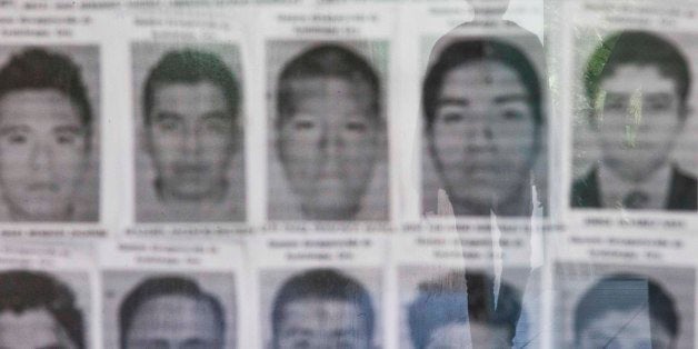 A university student is reflected in a glass display case containing the photos of the missing 43 students of the Rural Normal School of Ayotzinapa, Mexico, at the Central American University, UCA, in Managua, Nicaragua, Monday, Nov. 18, 2014. The 43 teachers-school students disappeared at the hands of a city police force on Sept. 26 in the town of Iguala, Mexico. (AP Photo/Esteban Felix)