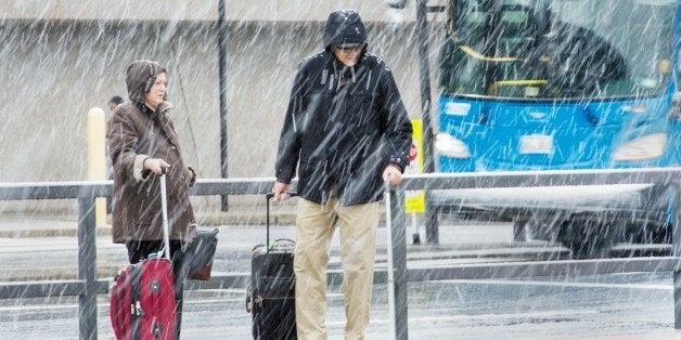 Airline passengers at Dulles International Airport outside Washington, DC, in Virginia, arrive to snow showers on the busiest travel day of the year November 26, 2014. Hundreds of flights were cancelled or delayed Wednesday in the US northeast as a winter storm delivered freezing rain and snow ahead of the Thanksgiving holiday, one of the year's biggest travel weekends. A wintry mix was falling in Boston, Philadelphia, New York and Washington, according to the National Weather Service, which forecast 'havoc' for travelers along the east coast from the Carolinas up through New England. AFP Photo/Paul J. Richards (Photo credit should read PAUL J. RICHARDS/AFP/Getty Images)