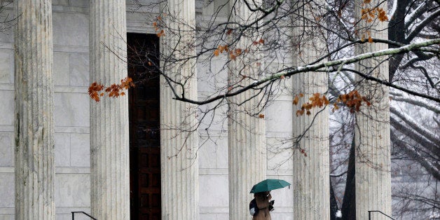 A person walks with an umbrella at Princeton University in Princeton, N.J., Monday, Dec. 9, 2013. The Ivy League school has begun vaccinating nearly 6,000 students to try to stop an outbreak of type B meningitis. The vaccinations were recommended by the U.S. Centers for Disease Control and Prevention. The vaccine is being made available to all undergraduates, as well as graduate students who live in dorms and employees with certain medical conditions. Seven students and one prospective student who was visiting campus have been stricken by potentially life-threatening type B meningococcal disease since March. None of the cases has been fatal. (AP Photo/Mel Evans)