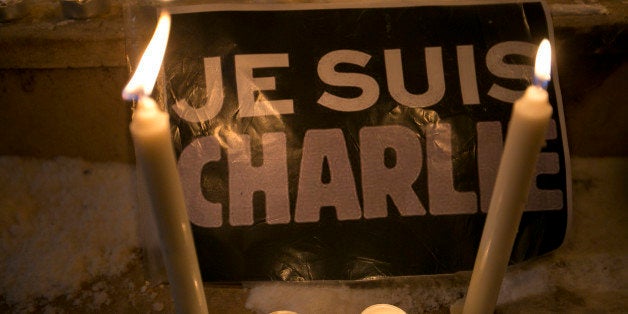 Candles are lit near a sign that read in French "I am Charlie" lights a candle during a demonstration in solidarity with those killed in an attack at the Paris offices of the weekly newspaper Charlie Hebdo in Kosovo capital Pristina, Wednesday, Jan. 7, 2015. Masked gunmen stormed the the satirical newspaper methodically killing at least 12 people Wednesday, including the editor, before escaping in a car. It was France's deadliest postwar terrorist attack. (AP Photo/Visar Kryeziu)