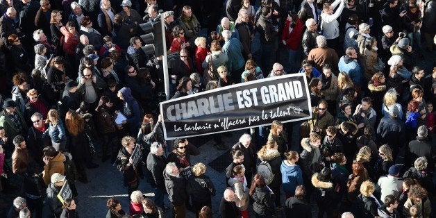 A people holds a sign reading 'Charlie is great, barbarism won t erase talent' during a demonstration attended by an estimated 45.000 on the old harbour in Marseille, southern France on January 10, 2015 as tens of thousands of people staged rallies across France following three days of terror and twin siege dramas that claimed 17 victims, including the victims of the first attack by armed gunmen on the offices of French satirical newspaper Charlie Hebdo in Paris on January 7. AFP PHOTO / ANNE-CHRISTINE POUJOULAT (Photo credit should read ANNE-CHRISTINE POUJOULAT/AFP/Getty Images)