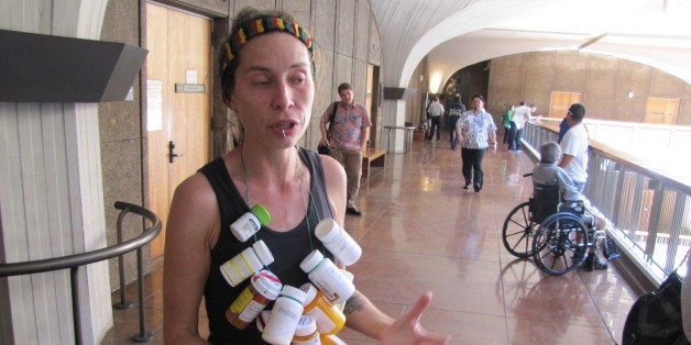 Michelle Tippens, of Honolulu, talks about the need for medical marijuana dispensaries at the Hawaii Legislature, Tuesday, Feb. 17, 2015. Tippens wore a necklace strung with more than a dozen prescription medicines that she says she was able to stop taking after she switched to medical marijuana. (AP Photo/Cathy Bussewitz)