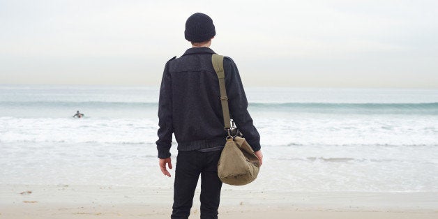 Man carrying luggage and looking at shore