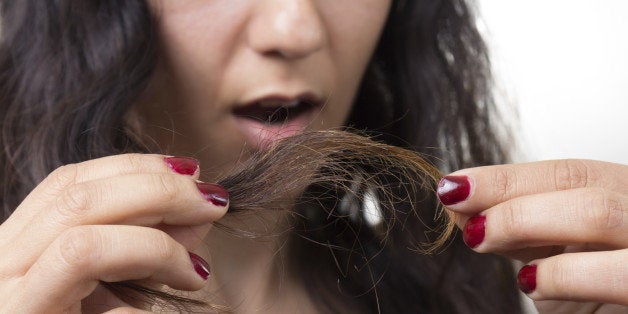 Girl looking at damaged splitting ends of hair.