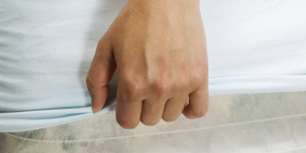 Horizontal female hand pulling bed sheet with mattress and box spring in background