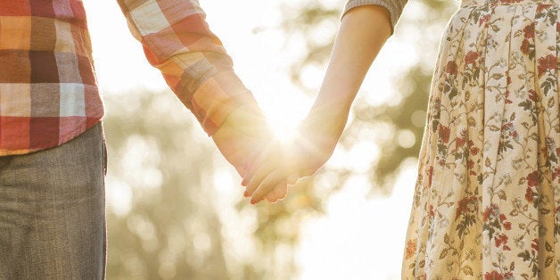 Young couple in love walking in the autumn park holding hands looking in the sunset