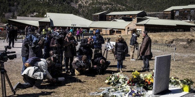 Journalists gather around a stele, carved in French, German, Spanish and English, in memory of the victims of the Germanwings Airbus A320 crash, in the small village of Le Vernet, French Alps, on March 27, 2015, near the site where an Airbus A320 crashed on March 24. The Germanwings co-pilot who flew his Airbus into the French Alps, killing all 150 aboard, hid a serious illness from the airline, prosecutors said on March 27 amid reports he was severely depressed. AFP PHOTO / JEFF PACHOUD (Photo credit should read JEFF PACHOUD/AFP/Getty Images)