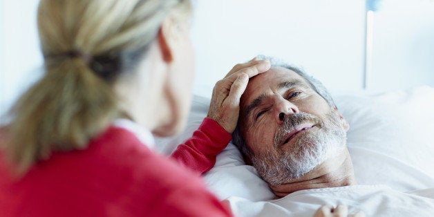 Rear view of woman caressing ill man in hospital ward