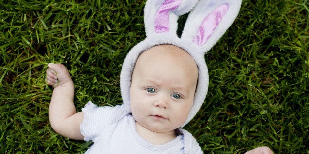 Baby lying in grass wearing Easter bunny ears