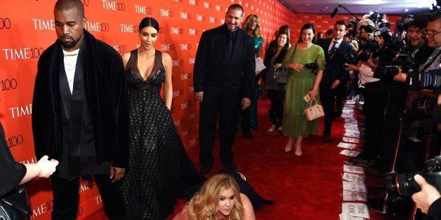 Honoree and Comedian Amy Schumer pretends to trip and fall on the floor in front of honorees Kim Kardashian (2nd-L) and Kanye West (L) as they attend the Time 100 Gala celebrating the Time 100 issue of the Most Influential People at The World at Jazz at Lincoln Center on April 21, 2015 in New York. AFP PHOTO / TIMOTHY A. CLARY (Photo credit should read TIMOTHY A. CLARY/AFP/Getty Images)