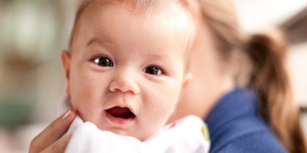 Surprised and smiling baby looking over Mum's shoulder.