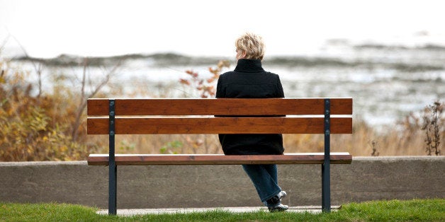 Mature woman sitting alone on park bench.