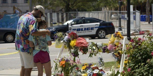 People visit a makeshift memorial near the Emanuel AME Church June 18, 2015 in Charleston, South Carolina, after a mass shooting at the Church on the evening of June 17, 2015. US police on Thursday arrested a 21-year-old white gunman suspected of killing nine people at a prayer meeting in one of the nation's oldest black churches in Charleston, an attack being probed as a hate crime. The shooting at the Emanuel African Methodist Episcopal Church in the southeastern US city was one of the worst attacks on a place of worship in the country in recent years, and comes at a time of lingering racial tensions. AFP PHOTO/BRENDAN SMIALOWSKI (Photo credit should read BRENDAN SMIALOWSKI/AFP/Getty Images)