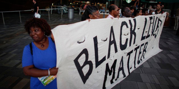 NEW YORK, NY - JUNE 21: A woman holds a banner during an interfaith candlelight vigil in solidarity with Emanuel AME Church in Charleston, South Carolina outside Barclays Center on June 21, 2015 in the Brooklyn borough of New York City. Nine people were fatally shot inside the historic African American church on June 17. Suspect Dylann Roof, 21, has been arrested and charged in the killings, which were racially motivated. (Photo by Kena Betancur/Getty Images)