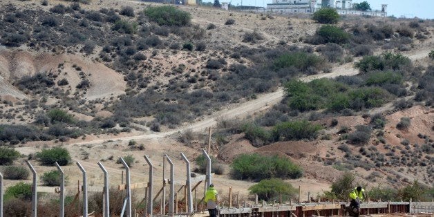 TO GO WITH AFP STORY BY AMER OUALI - Moroccan workers build a border fence near an Algerian military post (background) along