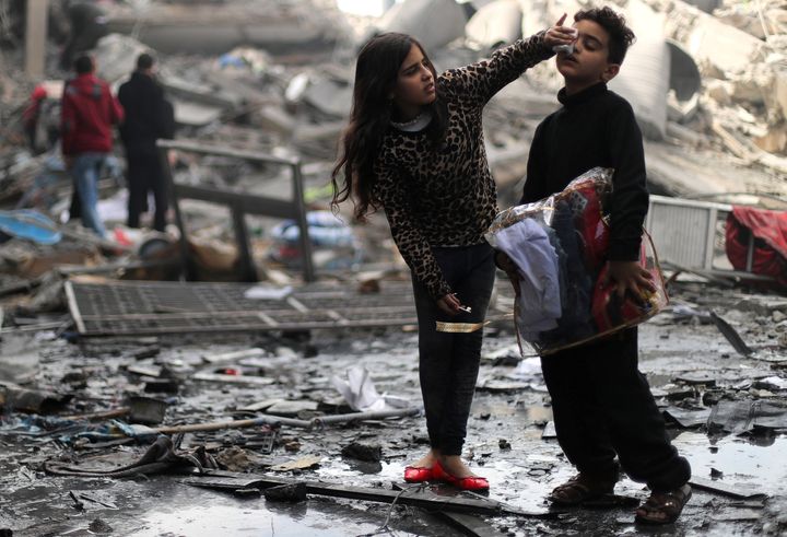 Ενα κορίτσι καθαρίζει το πρόσωπο του αδελφού του, στη λωρίδα της Γάζας, μετά από ισραηλινό πλήγμα που γκρέμισε γειτονικό σπίτι.