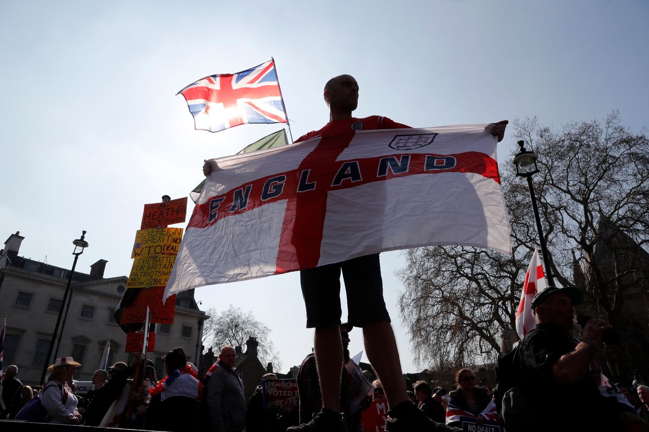 A Brexit supporter holds an England flag outside parliament