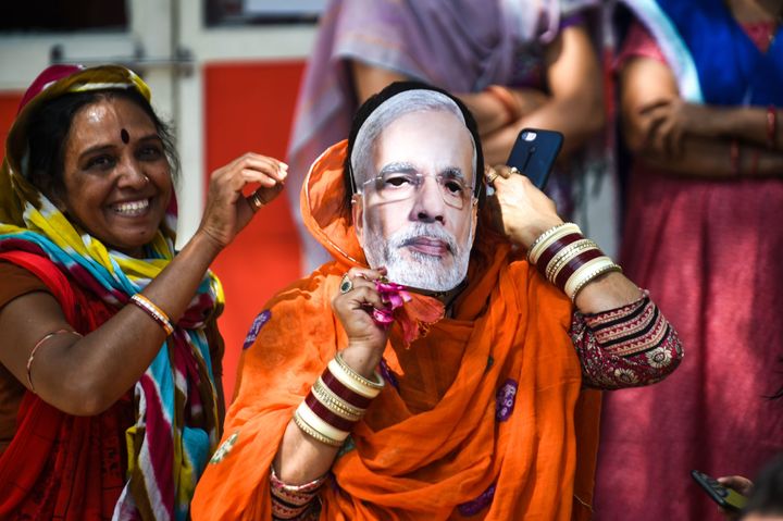 An Indian political supporter wears a mask of Indian Prime Minister Narendra Modi as she participates in Bharatiya Janata Party (BJP) President Amit Shah's road show in Ahmedabad on March 30, 2019.