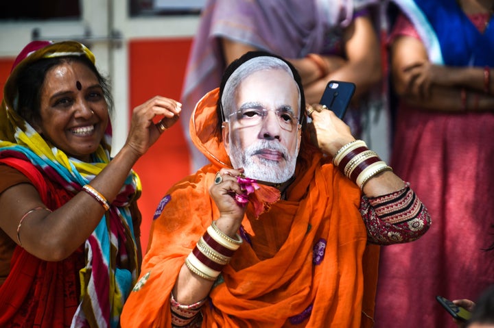 An Indian political supporter wears a mask of Indian Prime Minister Narendra Modi as she participates in Bharatiya Janata Party (BJP) President Amit Shah's road show in Ahmedabad on March 30, 2019.