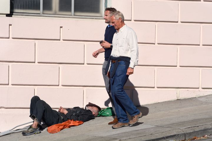 People walk past a person sleeping on a sidewalk in San Francisco in September 2018.