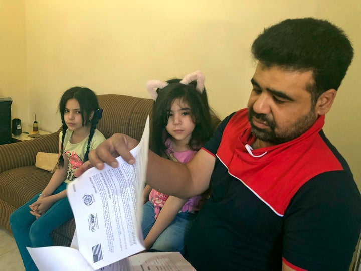 Syrian refugee Mahmoud Mansour, sitting with his daughters Sahar, 5, and Ruba, 11, holds documents for his U.S. resettlement application at his rented apartment in Amman, Jordan, Wednesday, June 27, 2018. 