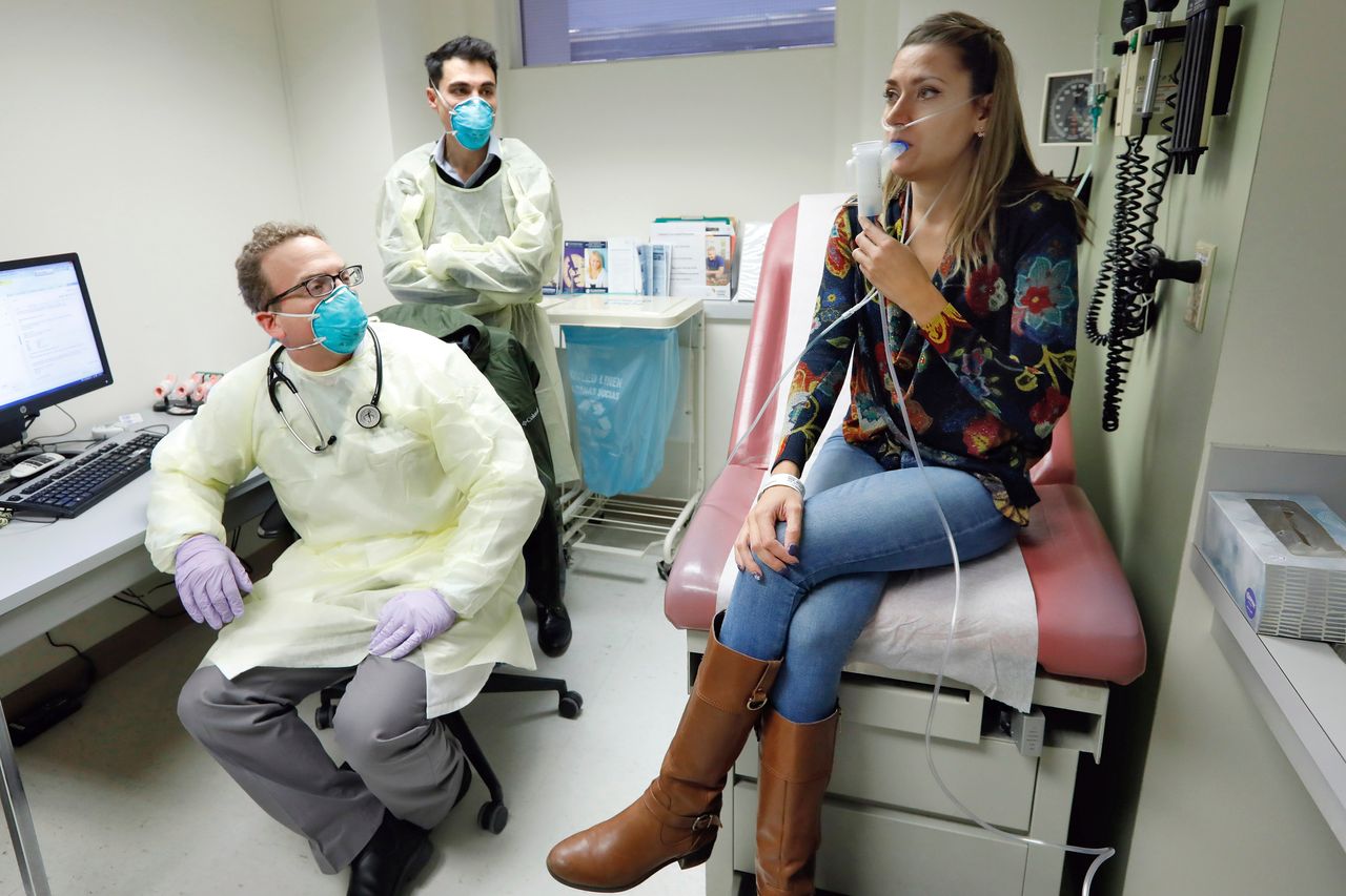 Yale pulmonary and critical care physician Dr. Jon Koff, left, and Yale University researcher Benjamin Chan, center, watch as Ella Balasa, 26, of Richmond, Virginia, inhales a bacteriophage, developed by Chan, during treatment at the Winchester Chest Clinic, in New Haven, Connecticut, on Jan. 17, 2019.