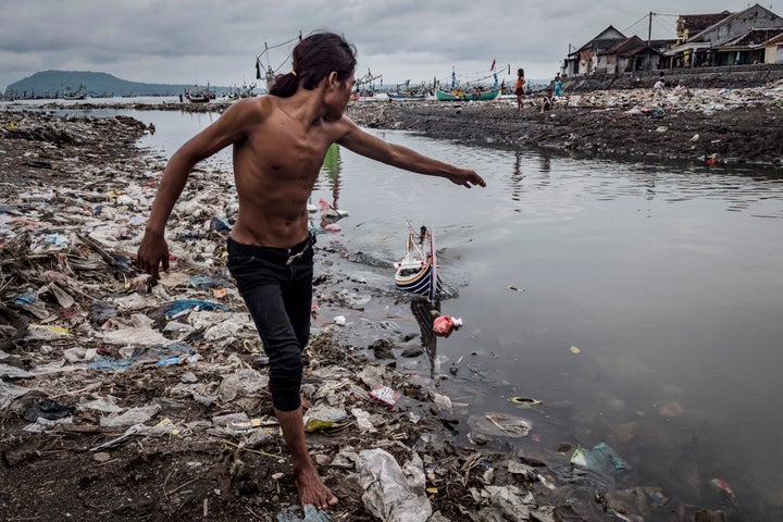 Children play at Muncar port in Indonesia. The city sits at the mouth of four rivers, into which communities toss their trash at a staggering rate, creating a deluge of plastic refuse that washes out to sea and collects on the shore.