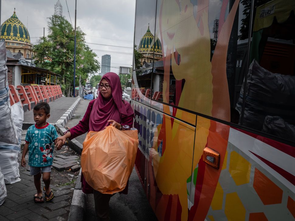 A woman brings used plastic bottles to exchange for bus tickets in Surabaya, East