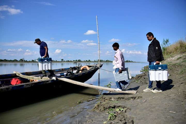 Election staff carrying Voter Verifiable Paper Audit Trail machines and an Electronic Voting Machine (EVM) board a boat to reach remote polling stations at Lahori Chapori in Golaghat district in the northeastern state of Assam. 