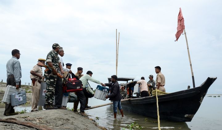 Officials carry EVMs on a boat, as security personnel watch over, to reach remote polling stations, in Dibrugarh, some 480 kms from Guwahati. 